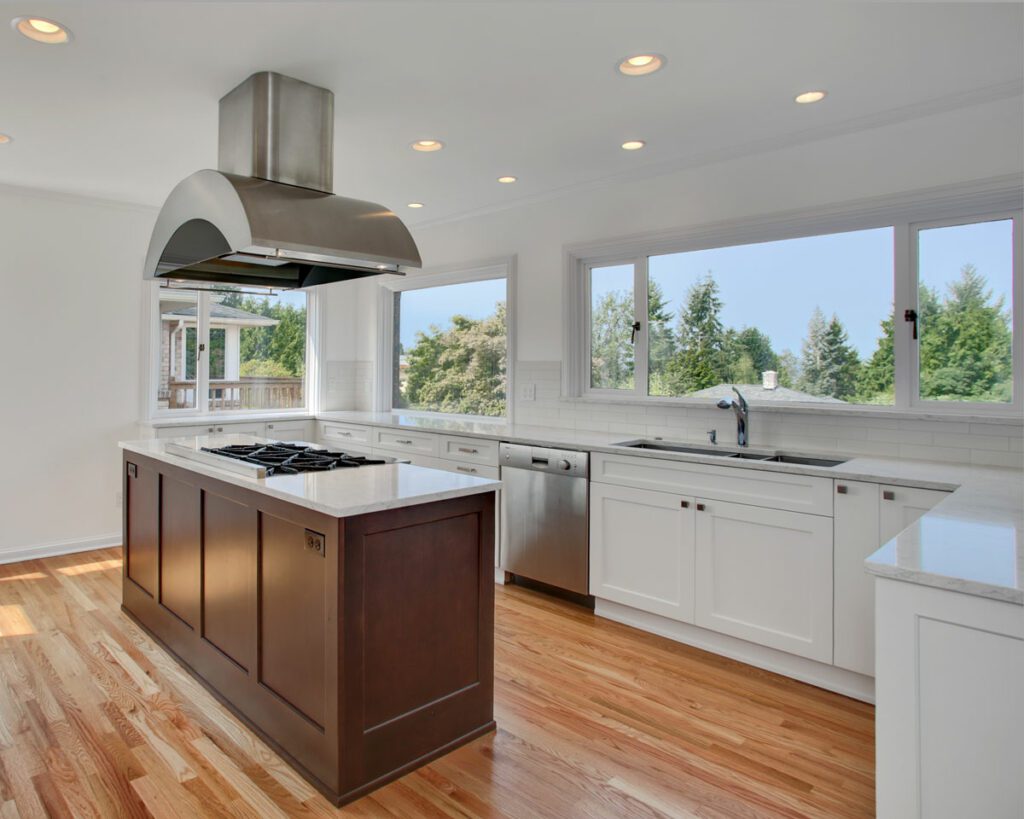 Bright white kitchen remodel with stained wood island with stovetop and hood